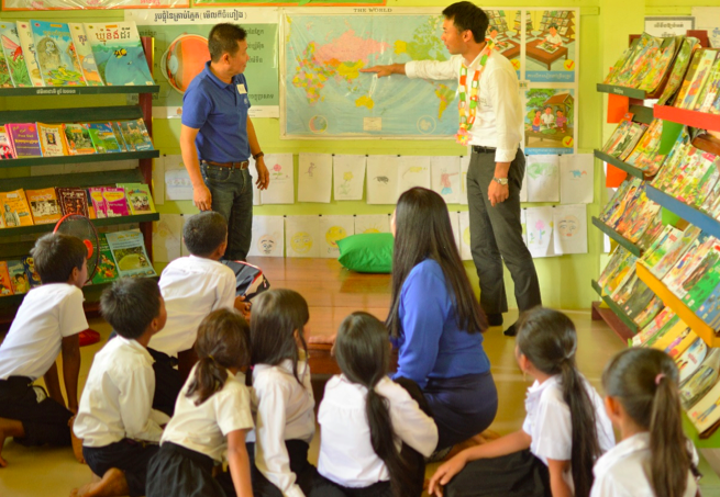 アビームの支援で完成したカンボジアの図書室で、世界地図を見せながら、授業をする矢野さん